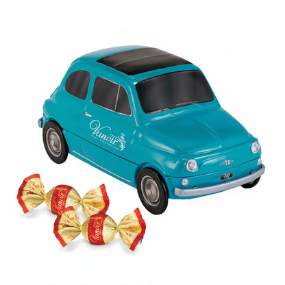 Scatola in latta decorativa a forma di macchinina vintage azzurra Vanoir con dettagli argentati, accompagnata da due cioccolatini incartati su sfondo bianco