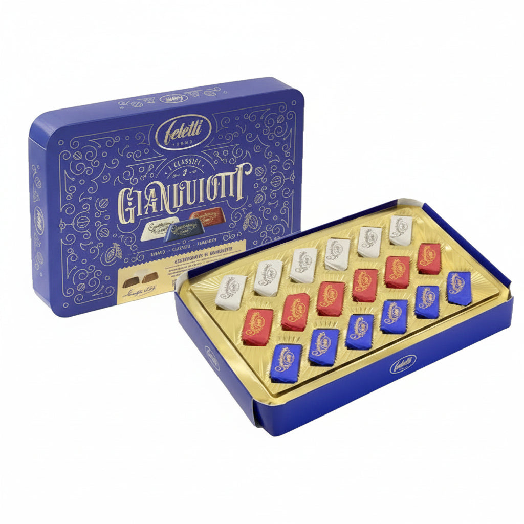Scatola in blu e oro Feletti I Classici Gianduiotti aperta con assortimento di cioccolatini incartati nei colori bianco, rosso e blu su sfondo bianco