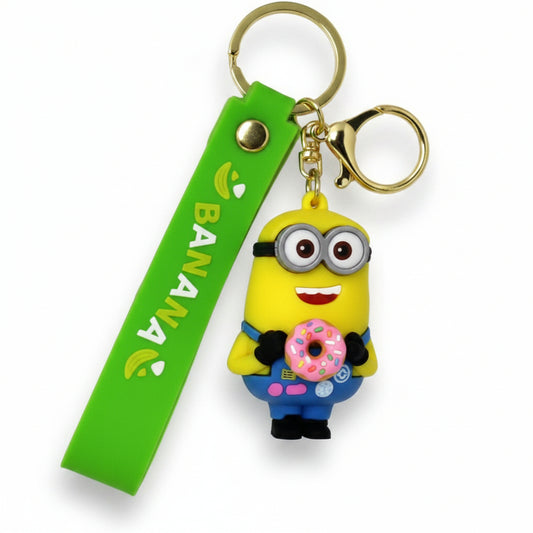Portachiavi in gomma verde e gialla Minions con un personaggio che tiene una ciambella rosa con zuccherini, anelli dorati e cinturino con scritta su sfondo bianco