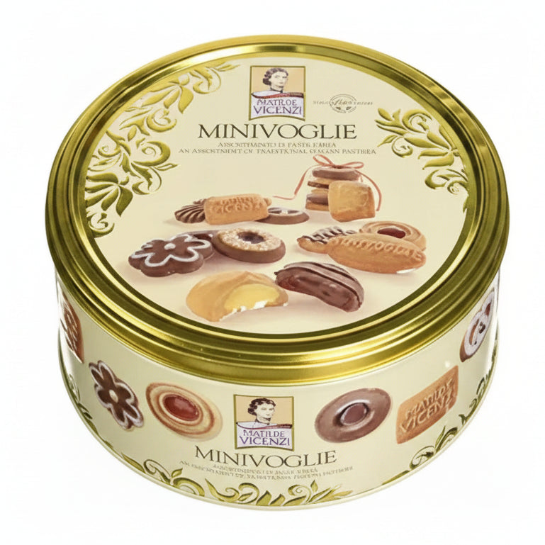Scatola in latta rotonda color crema e oro Matilde Vicenzi Minivoglie con immagini di pasticcini e biscotti assortiti sulla superficie su sfondo bianco