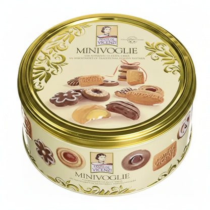 Scatola in latta rotonda color crema e oro Matilde Vicenzi Minivoglie con immagini di pasticcini e biscotti assortiti sulla superficie su sfondo bianco