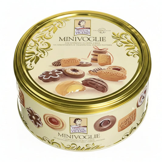 Scatola in latta rotonda color crema e oro Matilde Vicenzi Minivoglie con immagini di pasticcini e biscotti assortiti sulla superficie su sfondo bianco