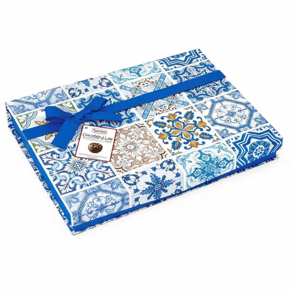 Confezione regalo quadrata Sorini con fantasia di maioliche blu e bianche, decorata con un nastro e un fiocco in tessuto blu su sfondo bianco