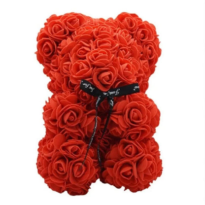 Orsetto decorativo realizzato interamente con rose artificiali rosse, arricchito da un elegante nastro in tessuto nero al collo su sfondo bianco