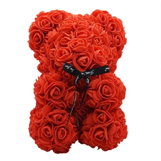 Orsetto decorativo realizzato interamente con rose artificiali rosse, arricchito da un elegante nastro in tessuto nero al collo su sfondo bianco